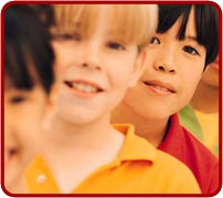 photo: children standing in a line. The first two are out of focus and a child wearing a red shirt is in the center of the picture