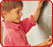 photo: a young boy standing at a chalk board writing the letter a and looking happy